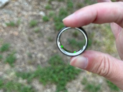 Holding the Oura Ring 4 to show the recessed sensors on the inside of the titanium band