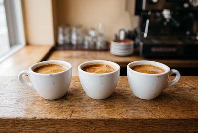 Three cups of fresh espresso with rich crema on a wooden counter
