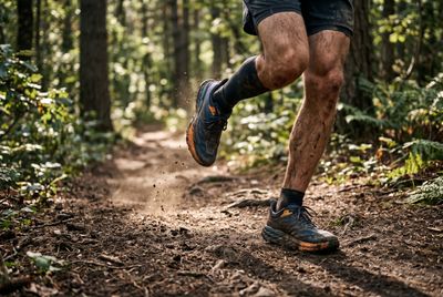 A runner's legs mid-stride on a soft forest trail