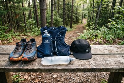 Trail-running shoes, a hydration vest and a flask laid out at a trailhead