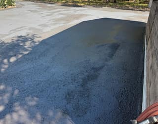 Half of a section coated and half still bare, showing the color difference between sealed and unsealed asphalt