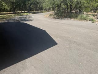 Our driveway a year after paving, before sealing. The surface had faded from black to gray along the curve.