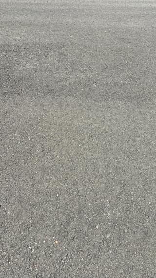 Close-up of the weathered asphalt texture after a year of Texas sun, with the fine aggregate starting to show