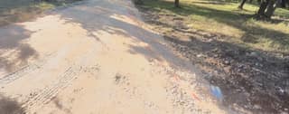 Orange paint layout lines on the compacted base marking the driveway edge before paving