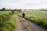 A relaxed runner on a gravel path through green fields