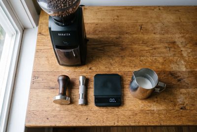 A flat-lay of espresso accessories: grinder, tamper, scale and milk pitcher