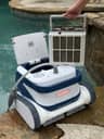 Lifting a dirty filter basket out of the Clear UV robotic pool cleaner on the pool deck