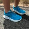 Blue Hoka Clifton 10 running shoes on a paved trail after a run