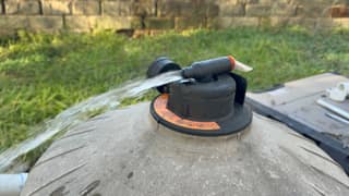 A steady stream of water spraying from the open air relief valve on top of a pool filter tank