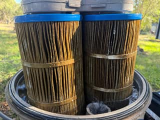 Dirty brown pleats on a pool filter cartridge seen inside the open filter tank