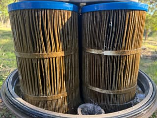 Dirty brown pool filter cartridge pleats inside an open filter tank