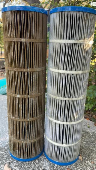 A dirty brown pool filter cartridge standing next to a rinsed light gray one