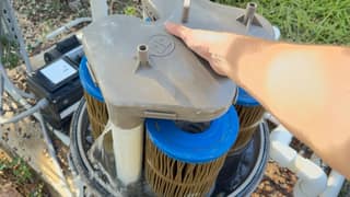 Top view of a hand lifting the manifold off the cartridges while water drains out