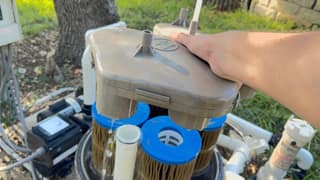 A hand lifting the top manifold off the cartridges in a Hayward SwimClear filter