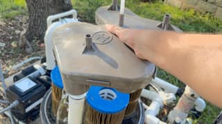 Hand lifting the manifold off the cartridges inside a Hayward SwimClear filter