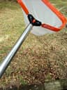 Pool leaf-rake bag being emptied onto the ground away from the water