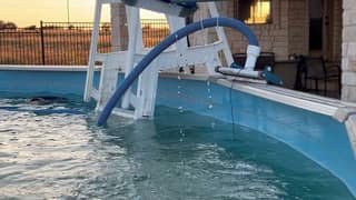 A corrugated vacuum hose lowered into an above-ground pool