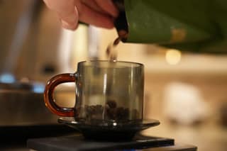 Beans falling midair from the bag into the cup