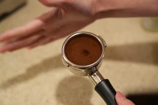 Freshly dosed grounds in the portafilter with a dimple in the center