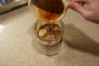 Pouring espresso into the glass of iced milk