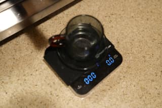 An empty cup on the scale, tared to zero, under the group head