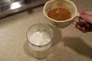 Holding the espresso cup over the glass of iced milk