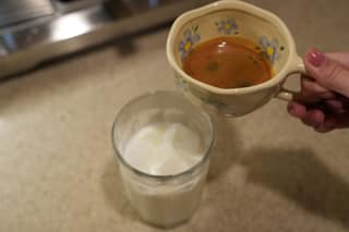 Thick crema on a double shot held over a glass of iced milk
