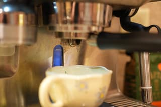 A drop of espresso hanging from the basket, not streaming