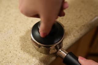 Pressing the top of the tamper with a finger to feel for level