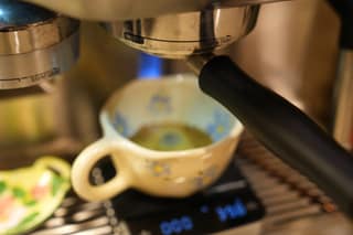 A finished shot in a cup on the scale under the portafilter