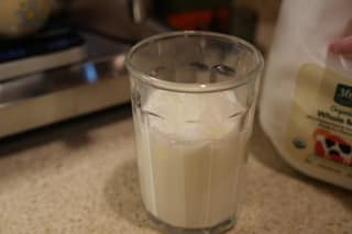A glass of iced milk next to a jug of whole milk