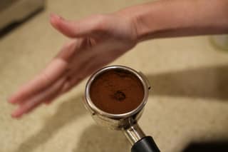 Leveling the grounds with a finger before tamping