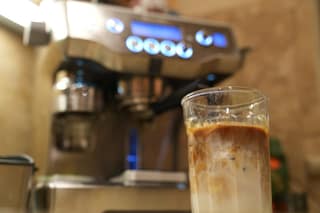 A layered iced latte in front of the Breville Oracle
