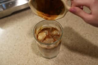 The last drops of espresso falling into the iced latte