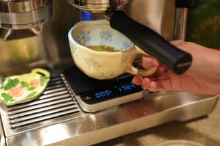 Lifting the espresso cup off the scale after the shot