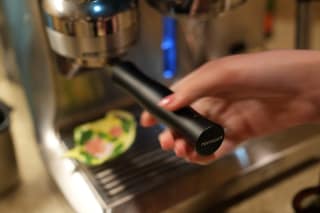 The bottomless portafilter seated in the grinder cradle
