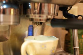 The first drop of espresso forming under the portafilter