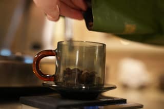 Pouring beans into a cup on the scale, nearly at the dose