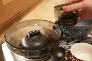 Pouring the weighed beans from the cup into the Oracle hopper
