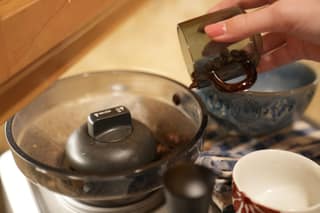 Pouring the weighed beans from the cup into the Oracle hopper