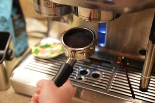A spent espresso puck in the portafilter over the drip tray