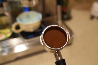 A tamped portafilter held in front of the espresso machine