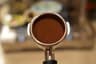 A tamped puck viewed straight on with the portafilter handle visible