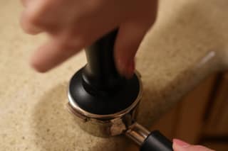 The tamper handle in a hand, about to press