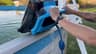 An older Nautilus CC Plus being lifted by its handle while water drains over an above-ground pool rail