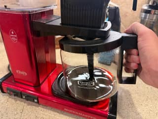 Removing the glass carafe from beneath the Moccamaster KBGV automatic brew basket