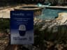PoolRx+ box held up in front of a backyard pool and spa