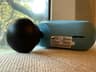 Second-generation Theragun Mini lying on its side with the Standard Ball attachment